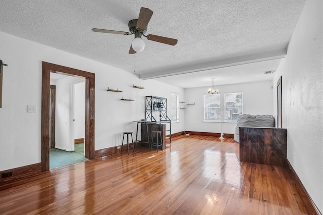 unfurnished living room with a textured ceiling, ceiling fan with notable chandelier, and hardwood / wood-style flooring