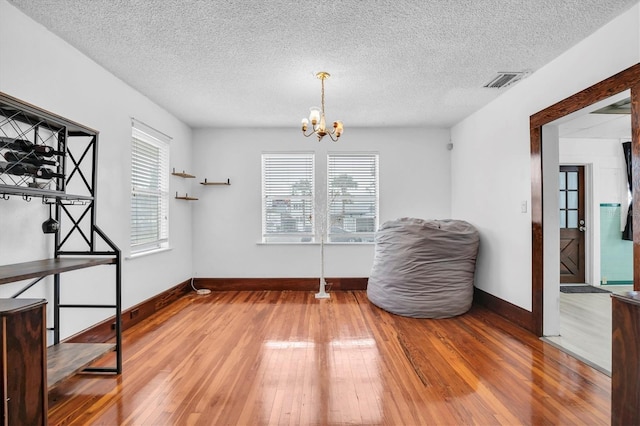 sitting room featuring hardwood / wood-style floors, a textured ceiling, and an inviting chandelier