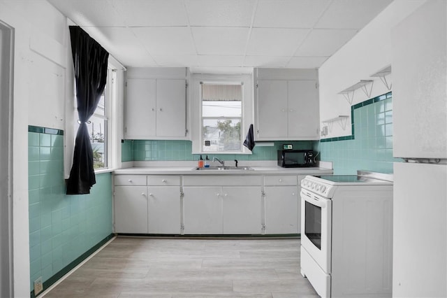 kitchen with white appliances, white cabinetry, a paneled ceiling, and sink