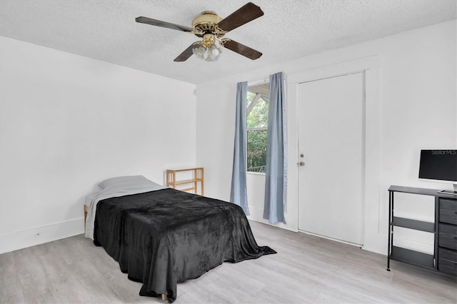 bedroom featuring ceiling fan, a textured ceiling, and light wood-type flooring