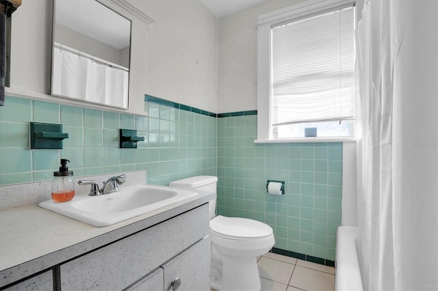 bathroom with toilet, vanity, tile patterned floors, and tile walls