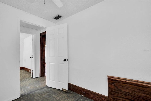 empty room featuring ceiling fan, a textured ceiling, and dark wood-type flooring