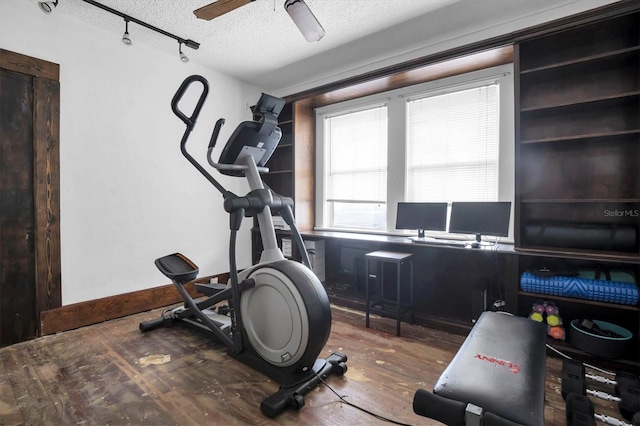 workout area featuring ceiling fan, dark hardwood / wood-style flooring, a textured ceiling, and track lighting