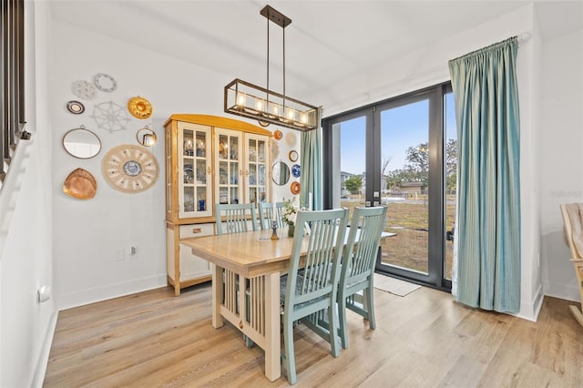 dining area featuring a notable chandelier, light hardwood / wood-style flooring, and french doors