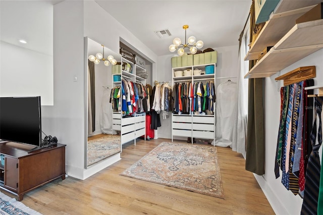 walk in closet featuring a notable chandelier and light hardwood / wood-style floors