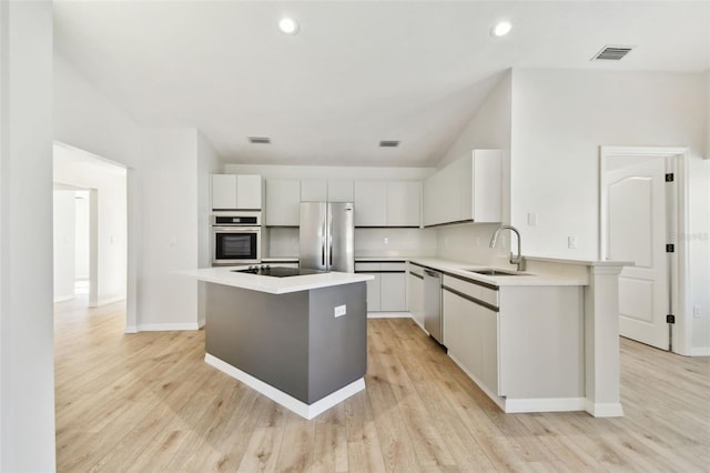 kitchen featuring white cabinetry, stainless steel appliances, a center island, and sink