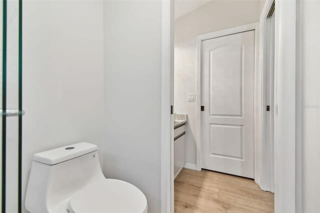 bathroom with wood-type flooring, toilet, and vanity