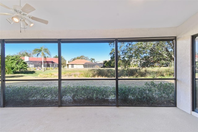 unfurnished sunroom featuring ceiling fan