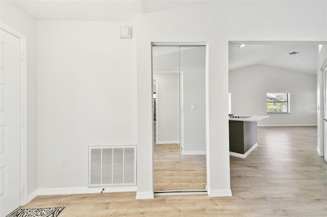 empty room with vaulted ceiling and light wood-type flooring