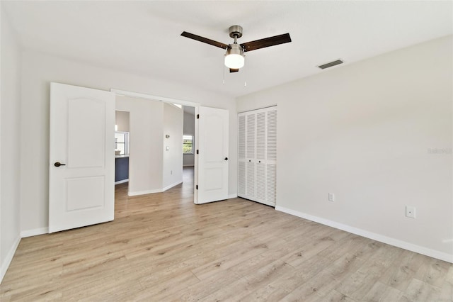 unfurnished bedroom featuring ceiling fan, a closet, and light wood-type flooring