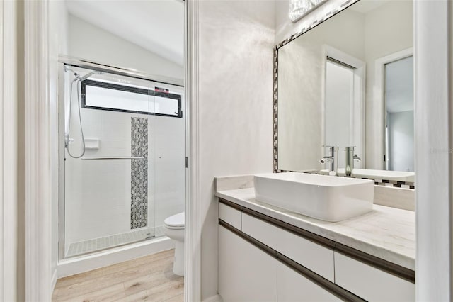 bathroom with lofted ceiling, toilet, wood-type flooring, vanity, and a shower with door