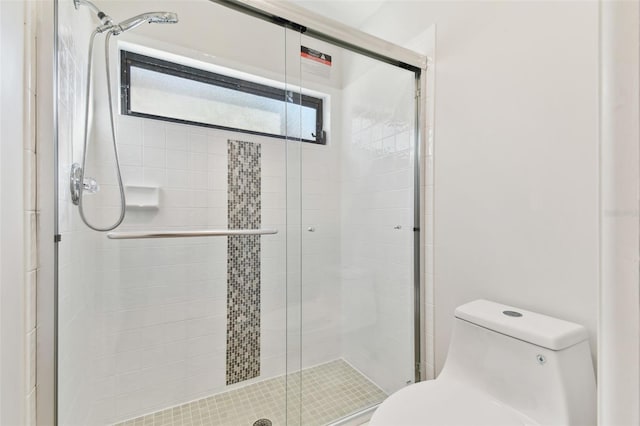 bathroom with a shower with shower door and toilet