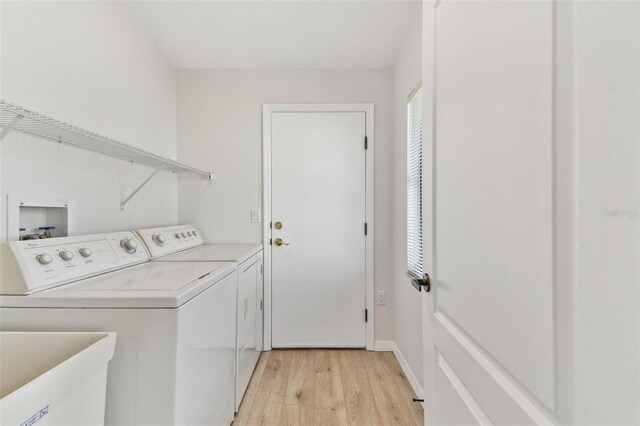 laundry room with washing machine and dryer, sink, and light hardwood / wood-style flooring