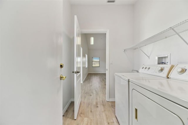 clothes washing area with light hardwood / wood-style floors and washing machine and clothes dryer