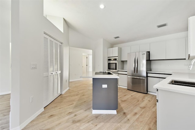 kitchen featuring sink, white cabinets, stainless steel fridge, a center island, and black electric stovetop