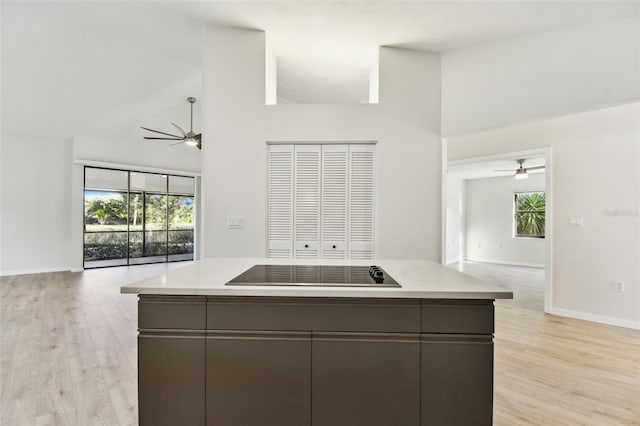 kitchen with dark brown cabinetry, black electric stovetop, a center island, and light wood-type flooring