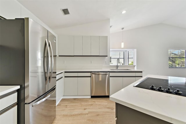 kitchen with lofted ceiling, sink, decorative light fixtures, appliances with stainless steel finishes, and gray cabinets