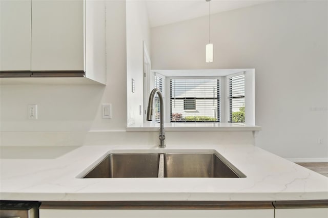 details with pendant lighting, white cabinetry, light stone countertops, and sink