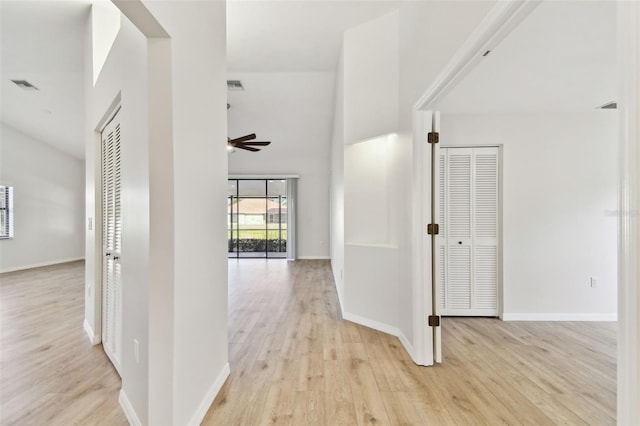 corridor with light hardwood / wood-style floors and a high ceiling