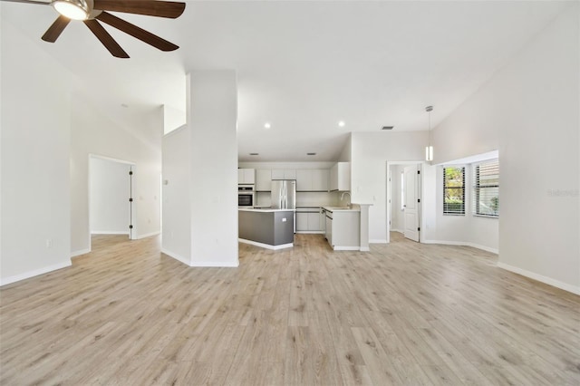 unfurnished living room featuring high vaulted ceiling, sink, ceiling fan, and light hardwood / wood-style flooring