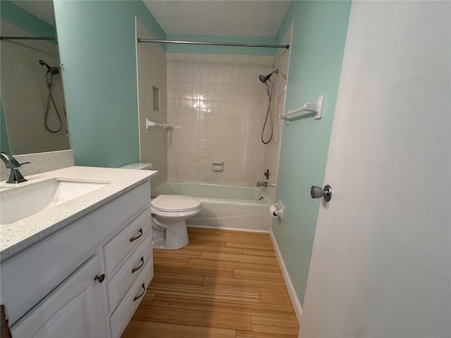 full bathroom with tiled shower / bath combo, vanity, wood-type flooring, a textured ceiling, and toilet