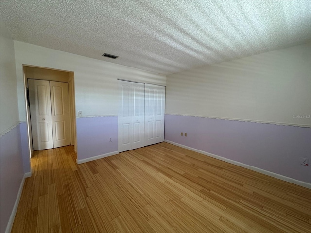 unfurnished bedroom with light hardwood / wood-style floors and a textured ceiling