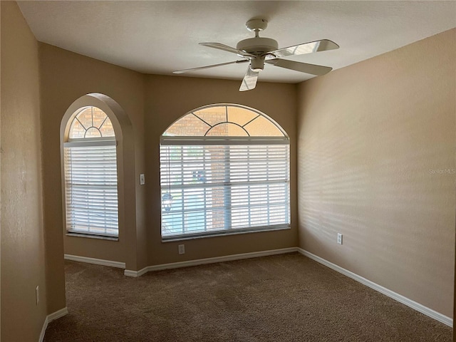 empty room featuring dark colored carpet and ceiling fan