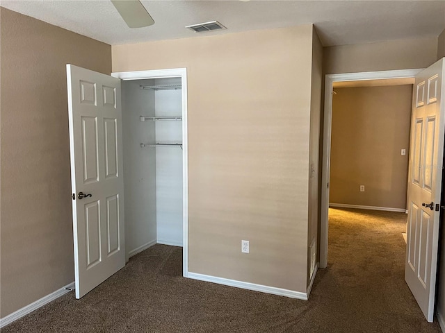 unfurnished bedroom featuring ceiling fan, a closet, and dark colored carpet