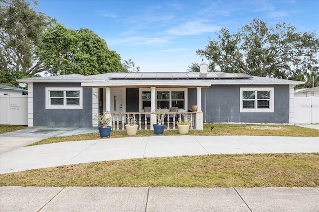 single story home with a porch, solar panels, and a front lawn