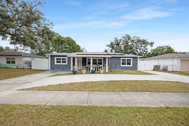 ranch-style house with a porch, a front lawn, and solar panels