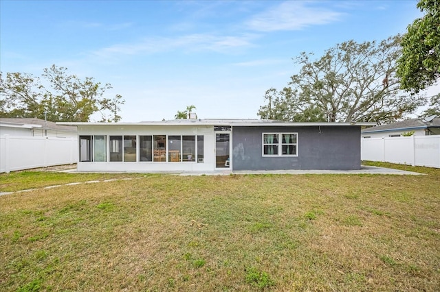 rear view of house featuring a yard and a sunroom