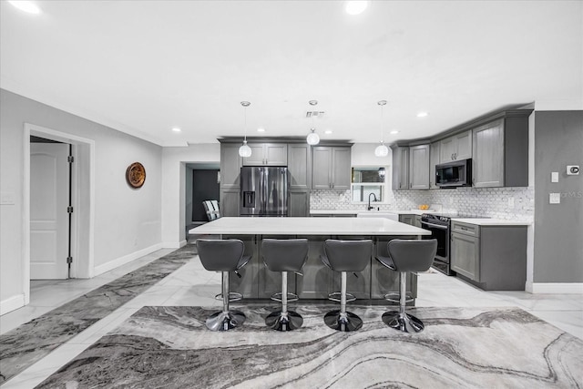 kitchen with a kitchen island, appliances with stainless steel finishes, a breakfast bar, decorative light fixtures, and gray cabinetry