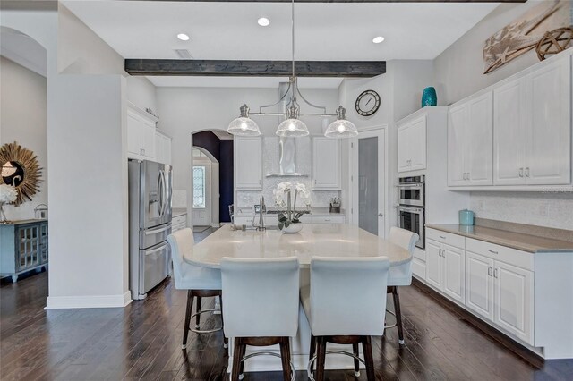 kitchen featuring appliances with stainless steel finishes, white cabinetry, beamed ceiling, and hanging light fixtures