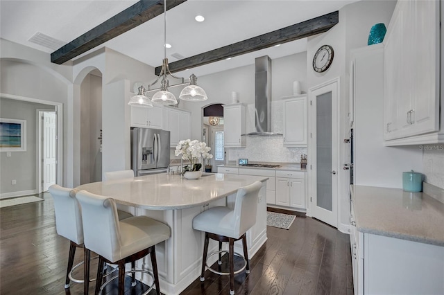 kitchen featuring stainless steel refrigerator with ice dispenser, white cabinets, and wall chimney range hood