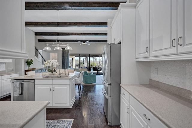 kitchen with pendant lighting, stainless steel appliances, beam ceiling, white cabinetry, and sink