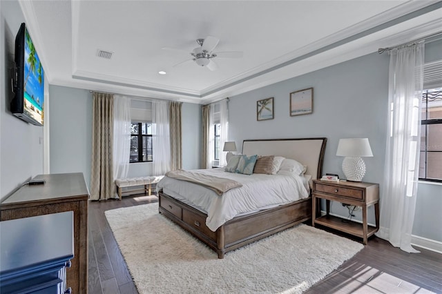 bedroom with dark hardwood / wood-style flooring, a raised ceiling, ceiling fan, and ornamental molding