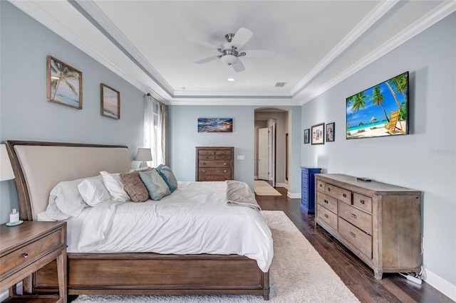 bedroom featuring dark hardwood / wood-style flooring, ceiling fan, a tray ceiling, and crown molding