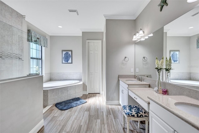 bathroom with a relaxing tiled tub, crown molding, wood-type flooring, and vanity