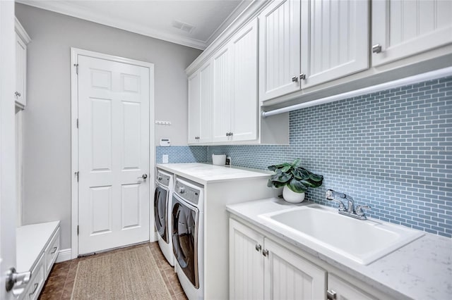 laundry area with sink, cabinets, independent washer and dryer, ornamental molding, and dark tile patterned floors