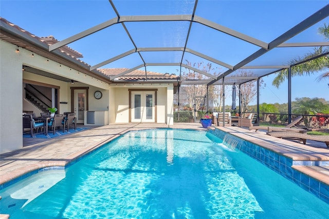 view of pool featuring a hot tub, pool water feature, a lanai, french doors, and a patio area