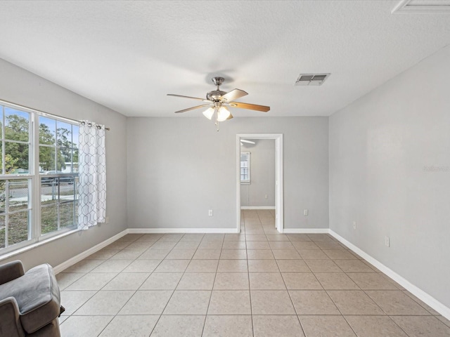 tiled spare room featuring a textured ceiling and ceiling fan