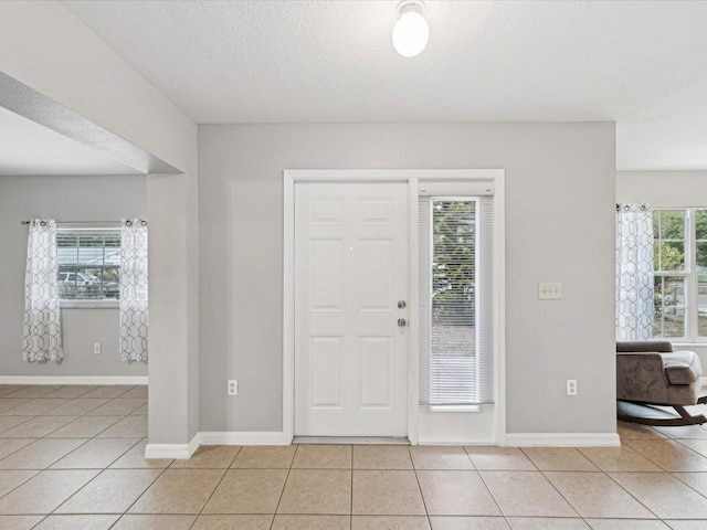 foyer entrance with a textured ceiling and light tile patterned flooring