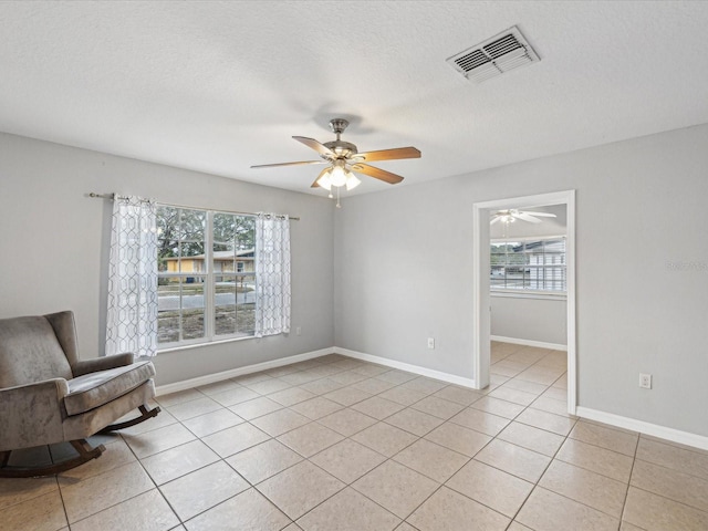 living area featuring plenty of natural light, light tile patterned flooring, and a textured ceiling