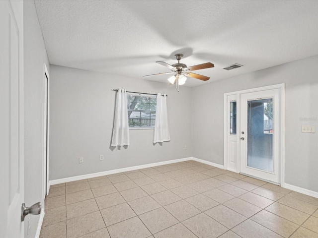 empty room featuring a textured ceiling, ceiling fan, and light tile patterned floors