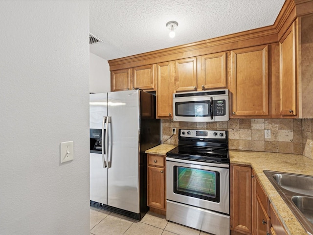 kitchen featuring light tile patterned floors, appliances with stainless steel finishes, decorative backsplash, and sink