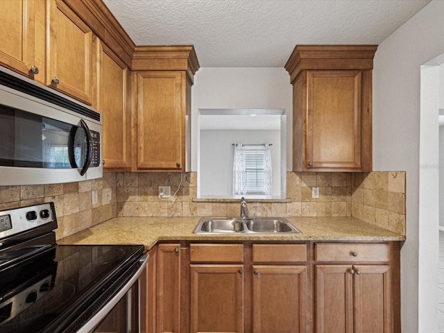 kitchen featuring sink, backsplash, appliances with stainless steel finishes, and a textured ceiling