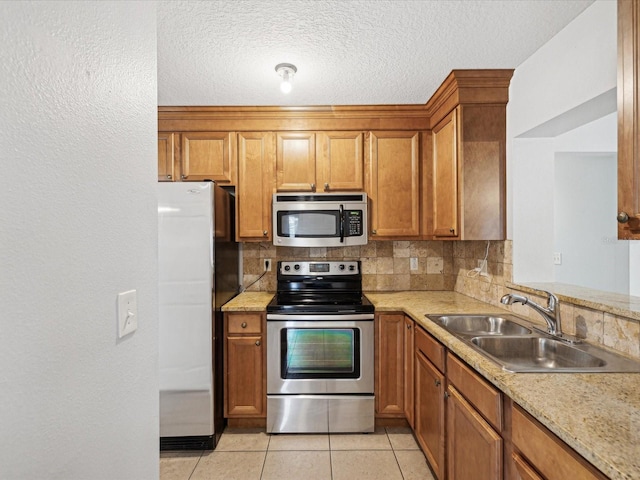 kitchen with light tile patterned floors, stainless steel appliances, decorative backsplash, a textured ceiling, and sink