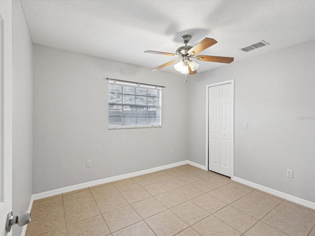 unfurnished room with a textured ceiling, ceiling fan, and light tile patterned floors