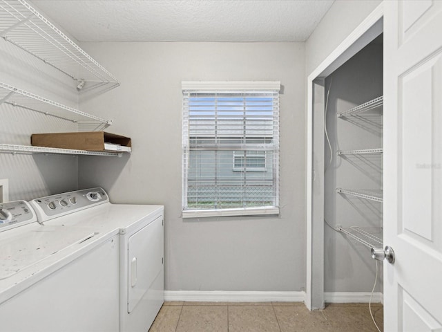 laundry room with plenty of natural light, light tile patterned floors, a textured ceiling, and washing machine and clothes dryer