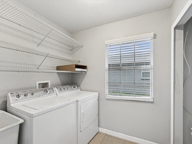 washroom featuring a textured ceiling, light tile patterned floors, washing machine and clothes dryer, and sink